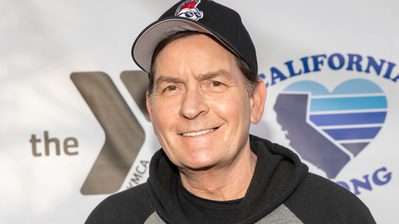 Charlie Sheen wearing a hoodie and a baseball cap on the red carpet