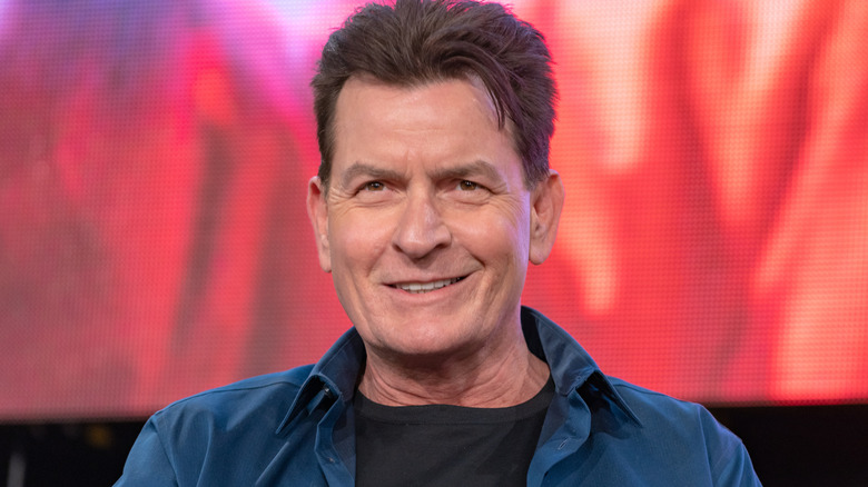 Charlie Sheen holding smiling while answering questions on a panel
