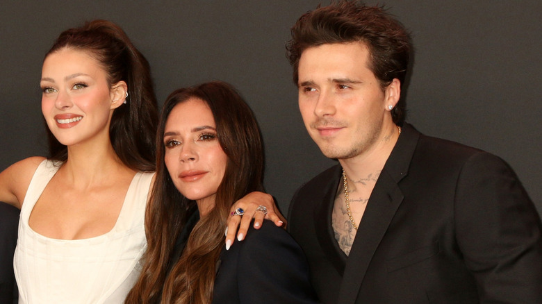 Nicola Peltz, Victoria Beckham, and Brooklyn Beckham smiling together for photo