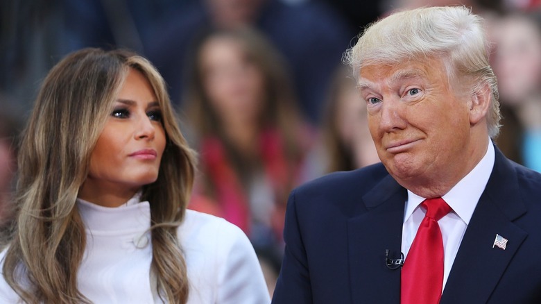 Sporting bronzer-heavy makeup, Melania Trump looks away from the camera as Donald Trump makes a face.