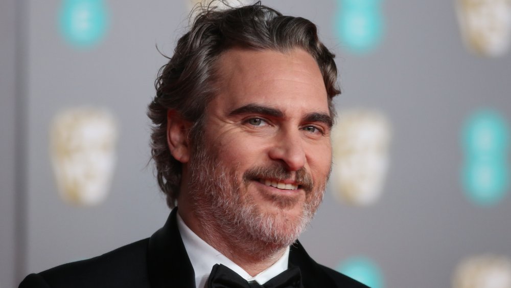 Joaquin Phoenix in a black tux, smiling on the 2020 BAFTAs red carpet
