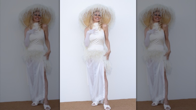 Pamela Anderson posing in all white at the "Le Raphia" Jacquemus show in 2022.
