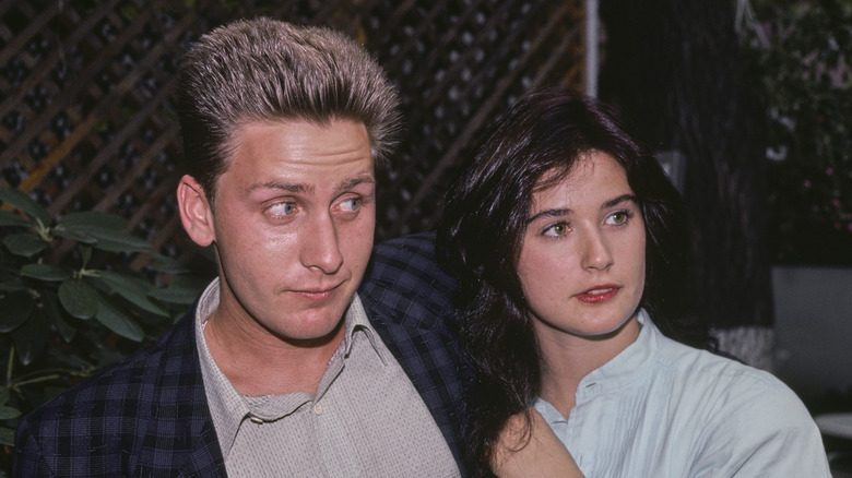 Emilio Estevez with Demi Moore posing in front of a wooden lattice