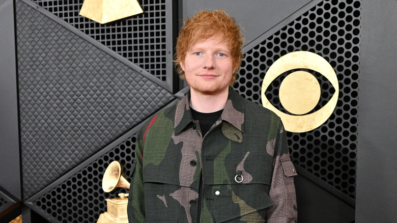 Ed Sheeran smiling with his mouth closed on the Grammys red carpet
