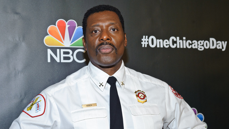 Eamonn Walker poses in fire chief outfit in front of NBC backdrop