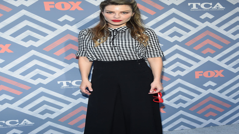 Lauren German in black and white gingham shirt in front of FOX backdrop