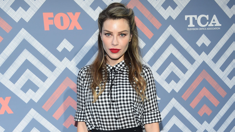 Lauren German in black and white gingham shirt in front of FOX backdrop