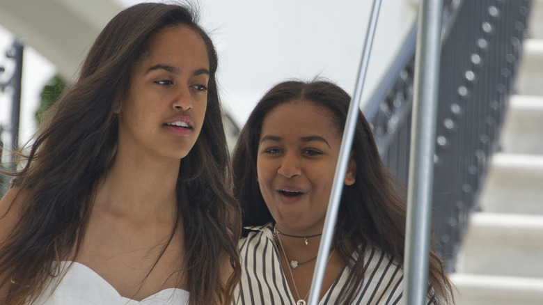 Sasha Obama makes a cheeky face while walking behind Malia Obama.