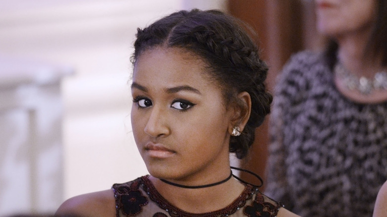 Wearing winged eyeliner and braided hair, Sasha Obama gives the camera a cold stare.
