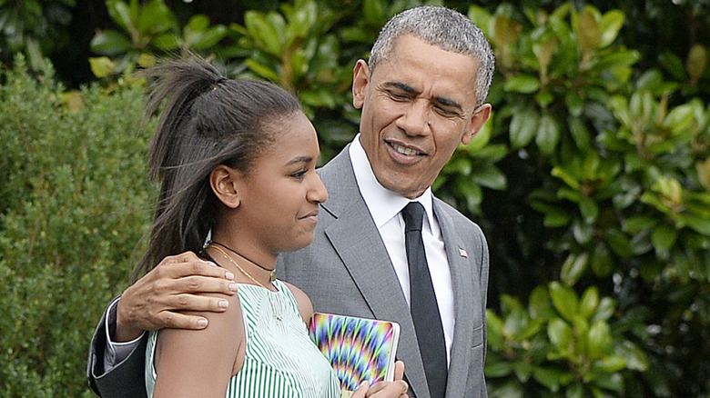 Barack Obama wraps his arm around a gently smiling Sasha Obama.