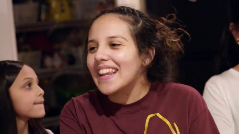Wearing a burgundy shirt, Selena Gutierrez is all smiles while surrounded by family.