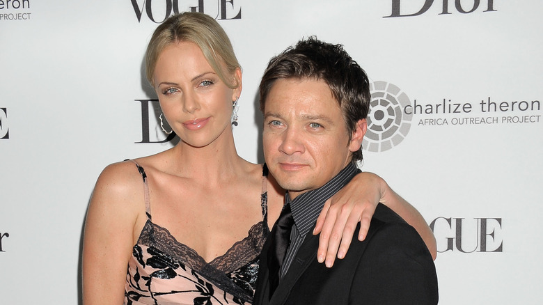 Charlize Theron with arm draped around Jeremy Renner