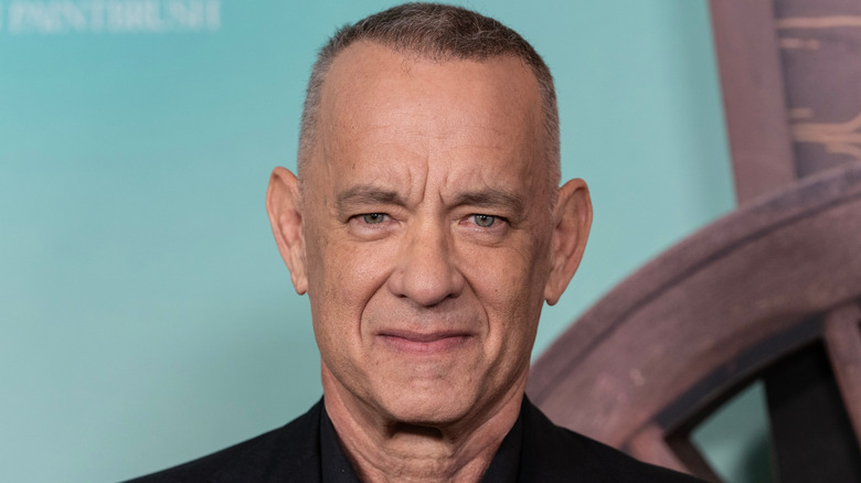 Tom Hanks smiling at an event with blue backrgound