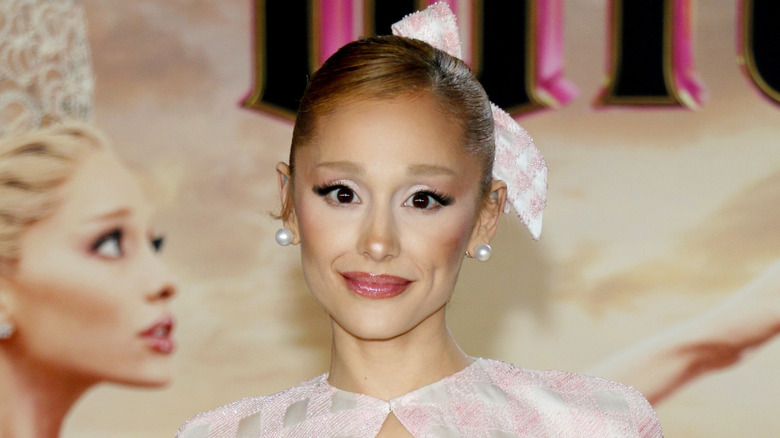 Ariana Grande smiling and wearing a bow at an event