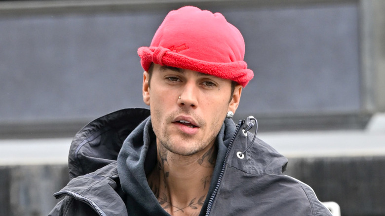 Justin Bieber walking and wearing a pink hat