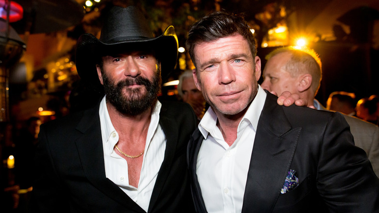 Tim McGraw posing with a hand on Taylor Sheridan's shoulder
