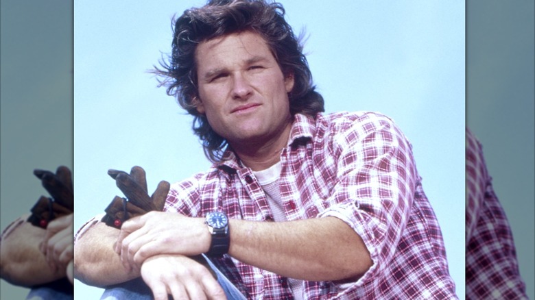 Kurt Russell posing in a plaid shirt for a promo shoot.