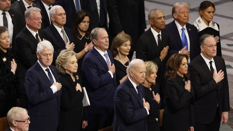 Marilyn Quayle, former U.S. Vice Presidents Al Gore and Mike Pence, Karen Pence, former U.S. President Bill Clinton, former Secretary of State Hillary Clinton, former U.S. President George W. Bush, Laura Bush, former U.S. President Barack Obama, U.S. President-elect Donald Trump, Melania Trump, U.S. President Joe Biden, first lady Jill Biden U.S. Vice President Kamala Harris and second gentleman Doug Emhoff standing with their hands over their hearts during the state funeral for former U.S. President Jimmy Carter at Washington National Cathedral