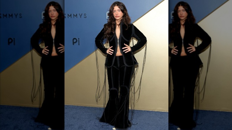 Odessa A'zion wearing a black velvet suit with strings hanging from it.
