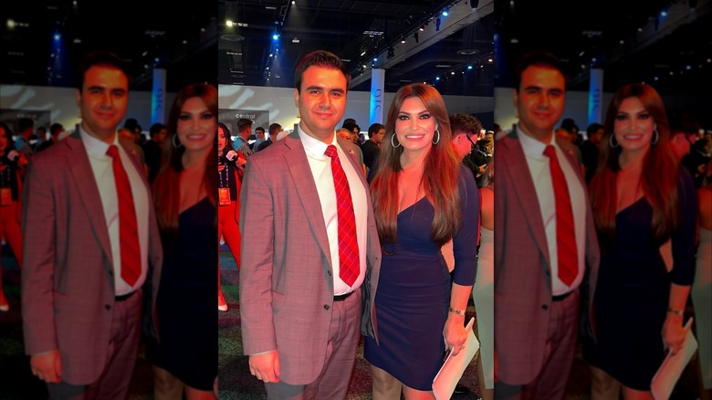 Sammy Balyasny and Kimberly Guilfoyle posing in a crowded dark room