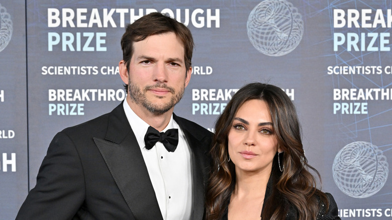 Ashton Kutcher and Mila Kunis posing while attending a red carpet event together