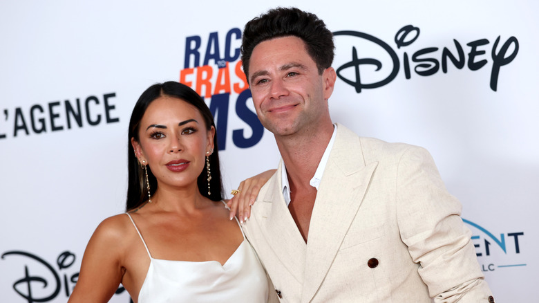 Janel Parrish and Sasha Farber wearing all white and posing at the 33rd Annual Race To Erase MS Gala