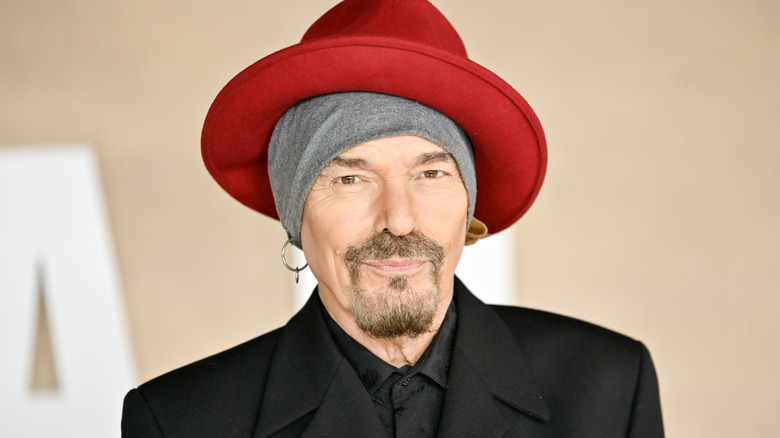 Billy Bob Thornton poses in gray headband and red hat