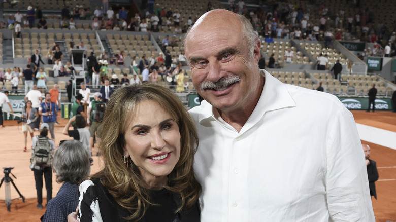 Dr. Phil and Robin McGraw smiling in a stadium.