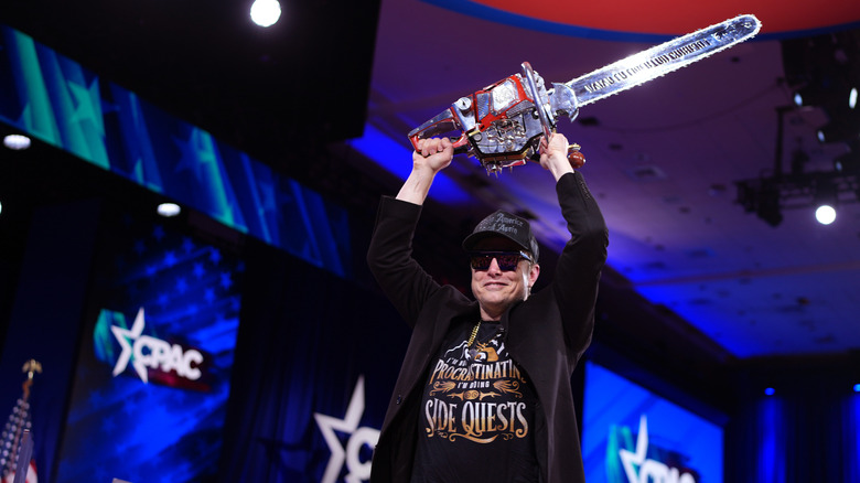 CEO of Tesla and SpaceX Elon Musk leaving the stage holding a chainsaw after speaking at the Conservative Political Action Conference (CPAC) at the Gaylord National Resort Hotel And Convention Center