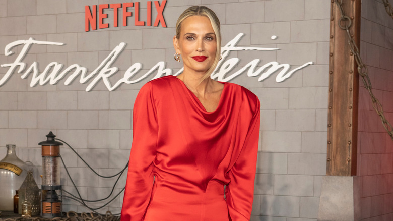 Molly Sims smiling in a red dress and matching lipstick.