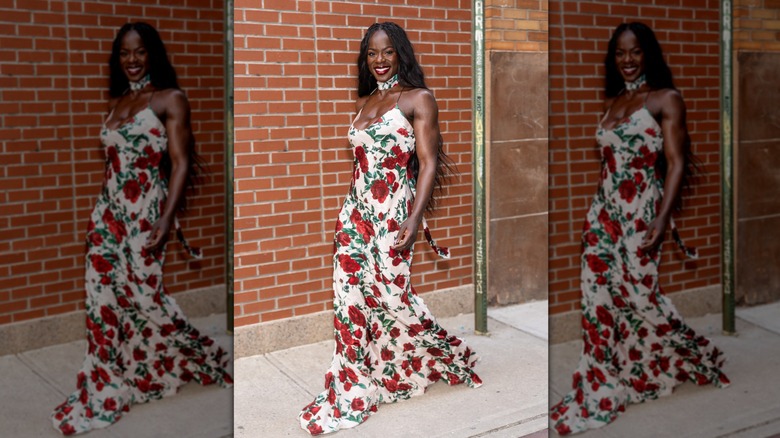 Tunde Oyeneyin smiling in a white maxi-dress featuring a red rose print.