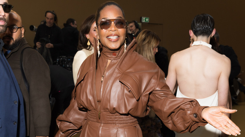 Oprah Winfrey shrugging to photographers at Paris Fashion Week.