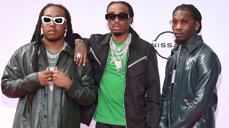Migos in black jackets, posing