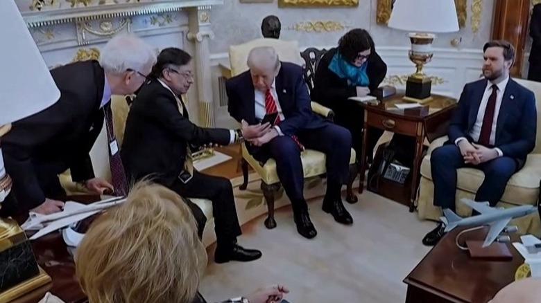 Donald Trump leans forward in his chair to look at Colombian President Gustavo Petro's phone in the Oval Office.