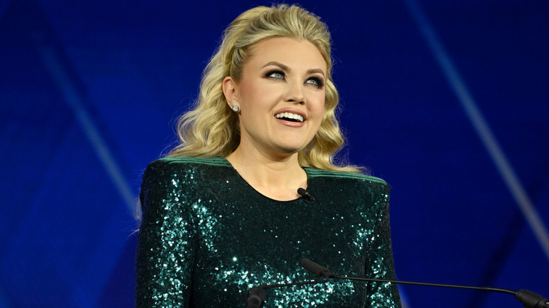 Erika Kirk smiling in sparkling green dress at podium