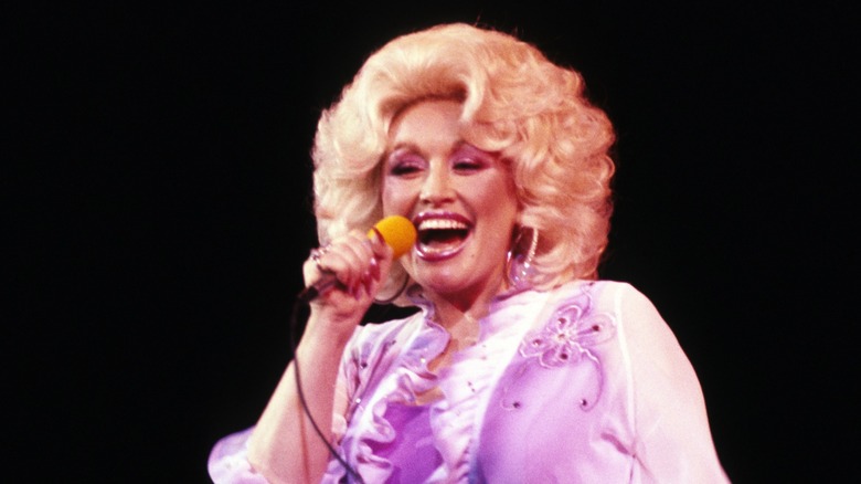 Dolly Parton singing while wearing lavender