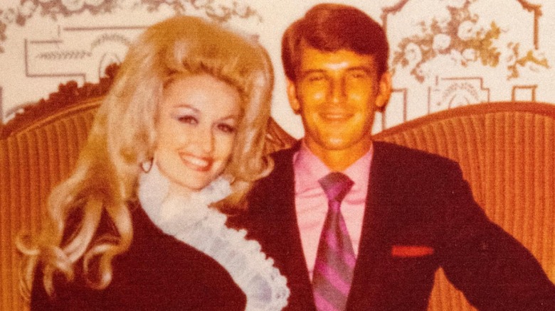 Dolly Parton and Carl Dean pose together on a sofa.