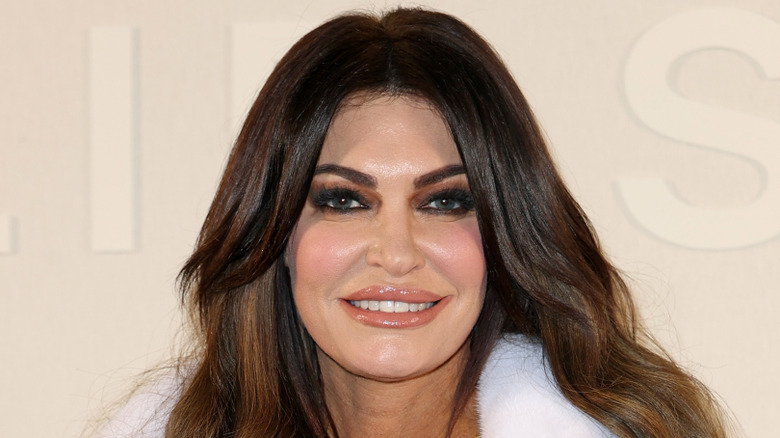 Kimberly Guilfoyle posing on the red carpet at Paris Fashion Week in a white fur