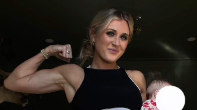 Riley Gaines flexing with her baby in workout clothes and a full face of makeup.