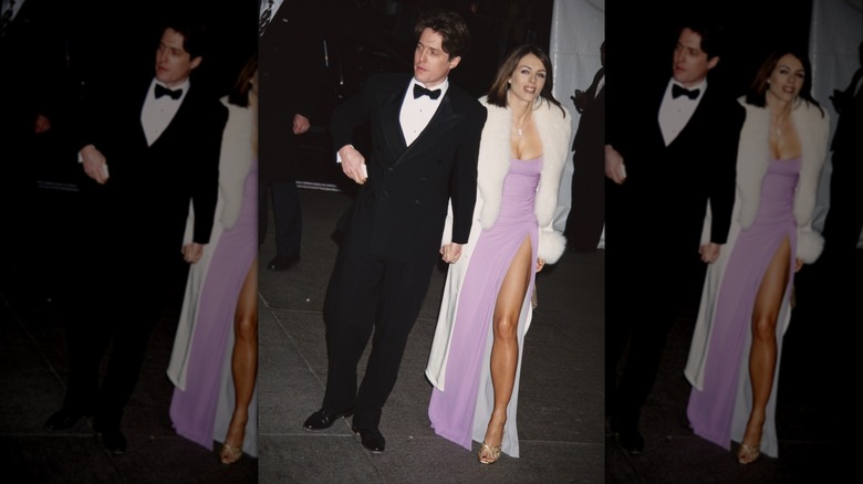 Hugh Grant in a tuxedo and Elizabeth Hurley in a lilac dress and fur-trimmed white coat at the 1995 Met Gala.