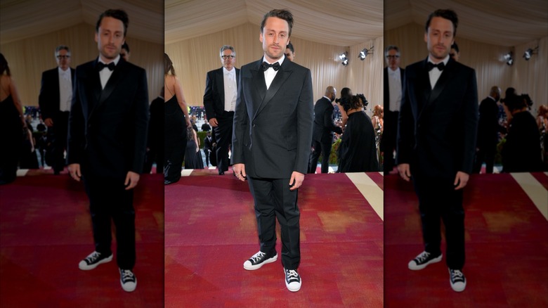 Kieran Culkin posing at 2022 Met Gala in a tuxedo and black sneakers.
