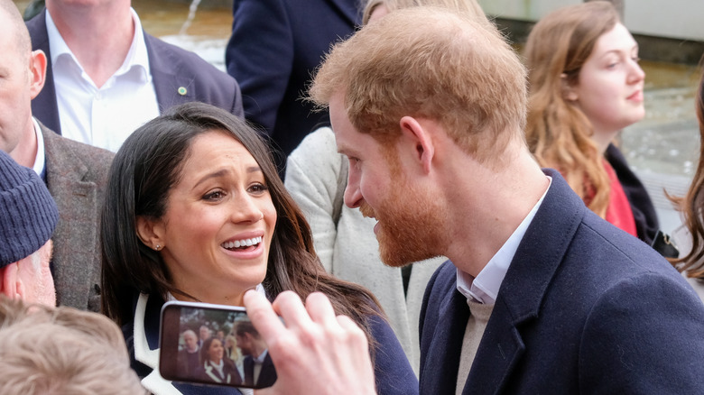 Prince Harry and Meghan Markle speaking to each other among a crowd of people