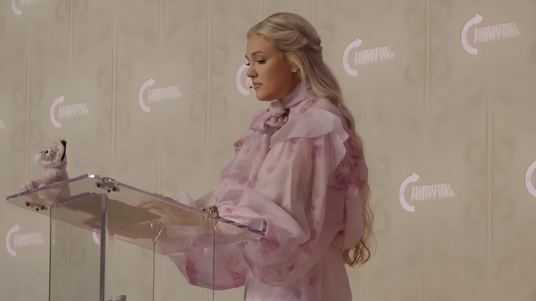 Erika Kirk in front of podium in an extravagant pink dress