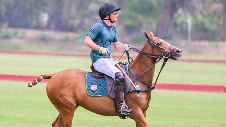 Prince Harry riding a horse while playing polo.
