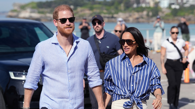 Prince Harry and Meghan Markle wearing blue and sunglasses.