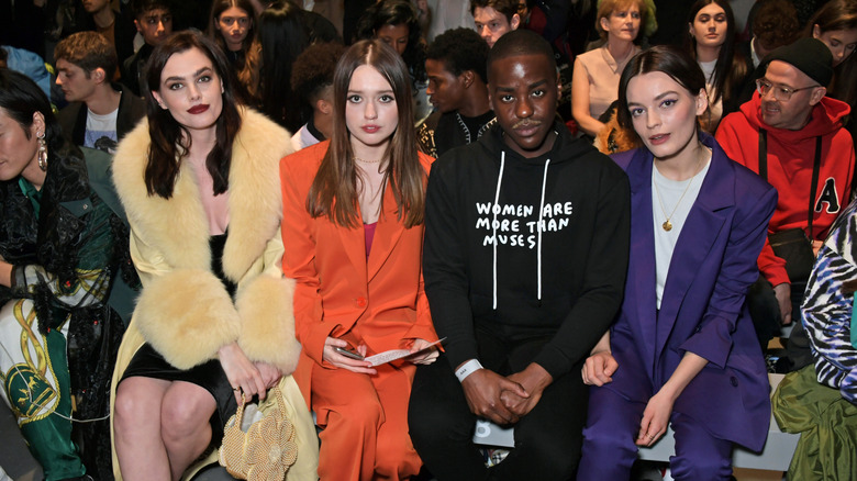 Aimee Lou Wood, Ncuti Gatwa, and Emma Mackey sitting at a fashion show and smiling