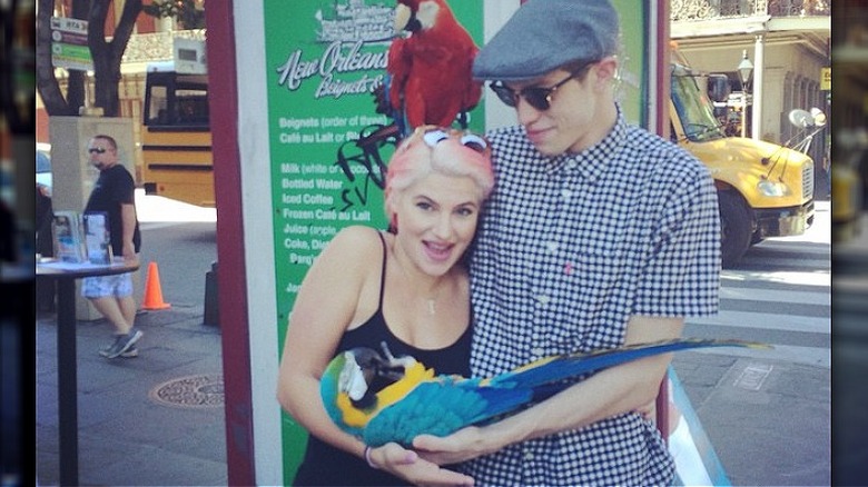 Carly Aquilino hugging Pete Davidson and holding a parrot