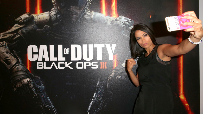 Rosario Dawson posing next to COD promo poster