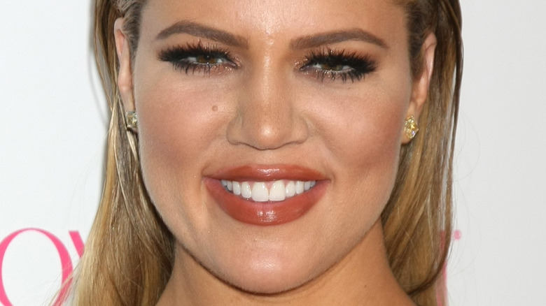 Khloe Kardashian smiles with hair slicked back