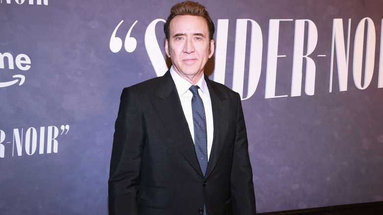 Nicolas Cage posing in a suit on the red carpet for 'Spider-Noir'